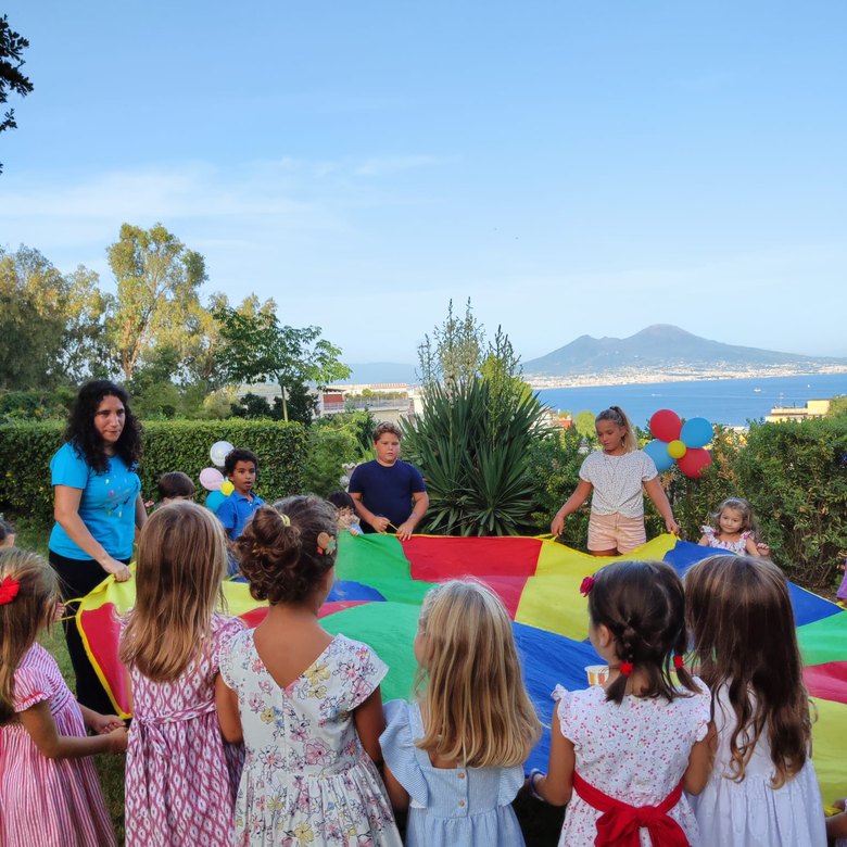 Bambini giocano con il paracadute arcobaleno, Vesuvio sullo sfondo